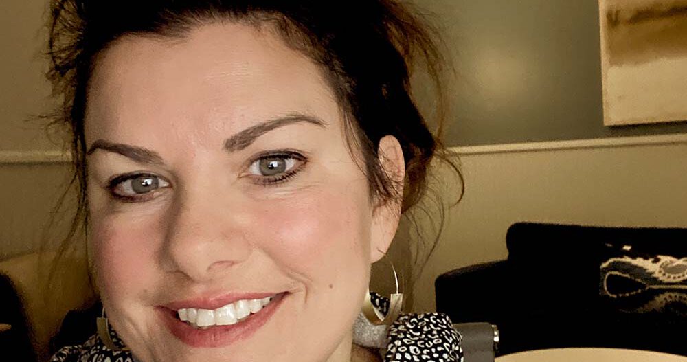 Headshot of Andrea Hofstad, LICSW, smiling, sitting in her office wearing stylish hoop earrings.
