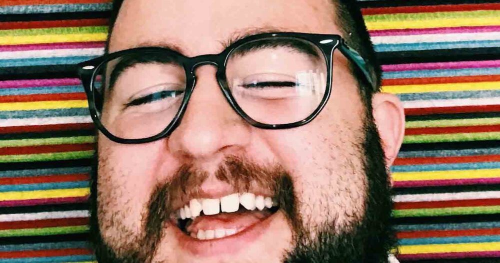 Headshot of Christian Russell, Client Access Specialist, flashing a very big smile.