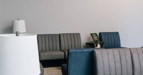 An interior photo of an Ellie Mental Health Therapy Clinic lobby with blue and gray chairs and two white table lamps.