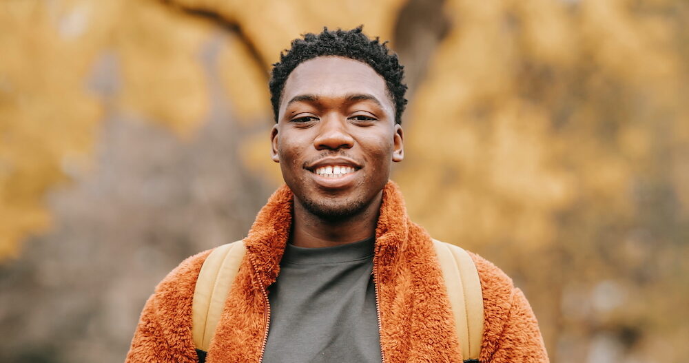 Man standing outside in the fall wearing a bright orange jacket